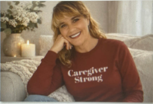 Kristen, founder of Kindcore Comforts, wearing a burgundy Caregiver Strong sweatshirt.